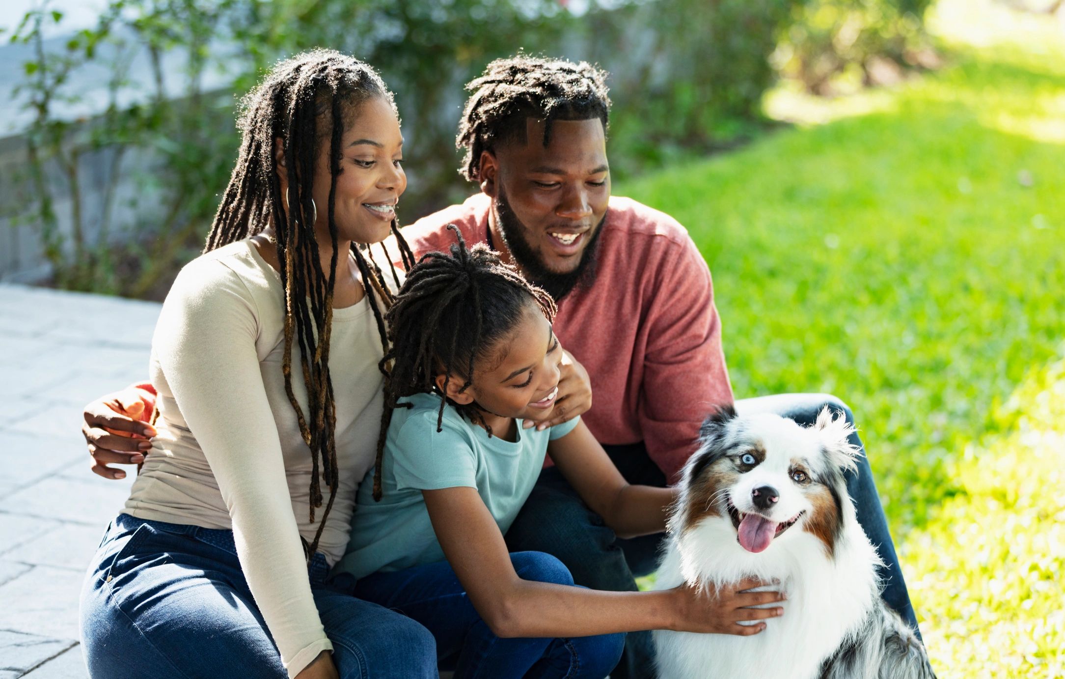Family petting dog in backyard
